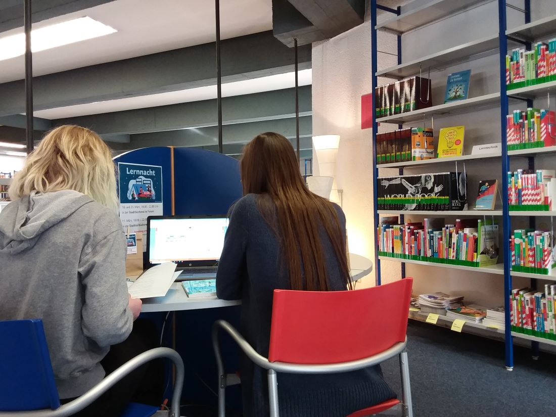 Schülerinnen sitzen in der Bibliothek vorm PC