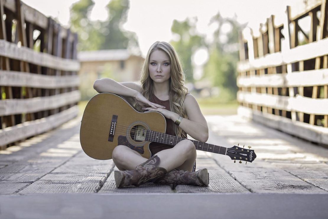 Frau sitzt auf Brücke mit Gitarre